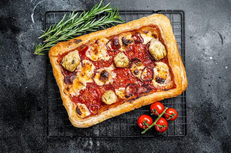 frische tomaten und artischockenherzen als zutaten für schnelle rezeptidee mit butterteig als pizzaboden