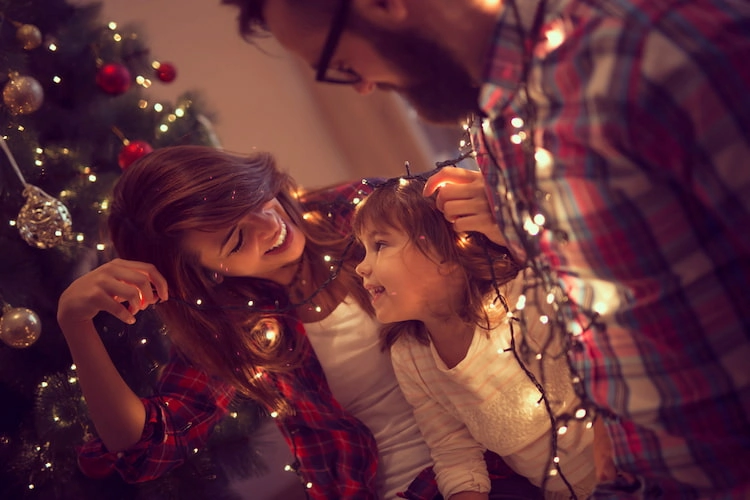 gemeinsam als familie den weihnachtsbaum aufstellen und mit traditioneller dekoration schmücken