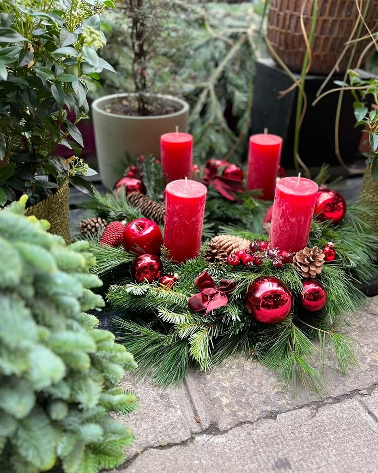 klassischer adventskranz in rot mit tannengrün und weihnachtskugeln