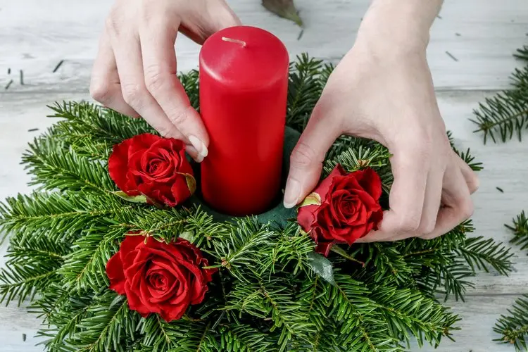 rote rosen köpfen und dem weihnachtlichen gesteck hinzufügen