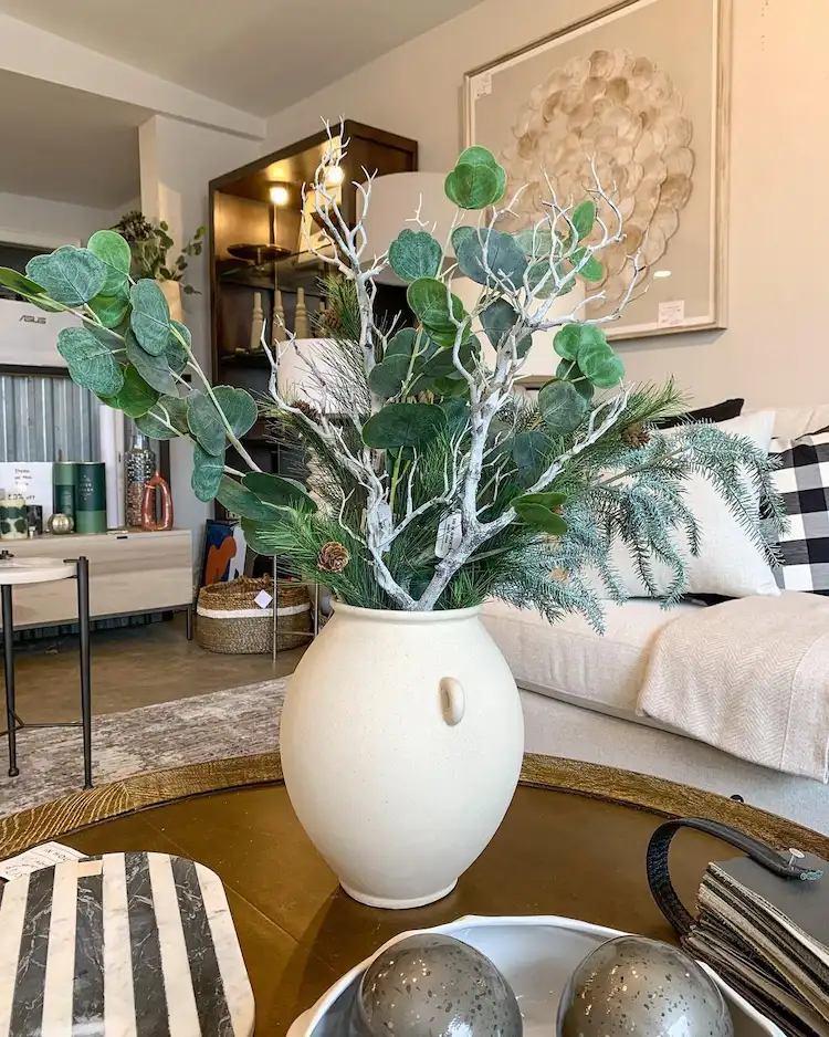 eine vase mit eukalyptus und tannenzweigen auf den couchtisch im winter stellen