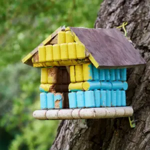 in blau und gelb gestrichenes vogelhaus aus korken und holz kann verschiedene vogelarten anlocken