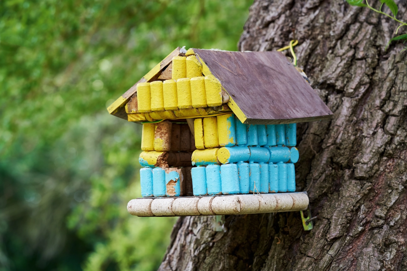 in blau und gelb gestrichenes vogelhaus aus korken und holz kann verschiedene vogelarten anlocken