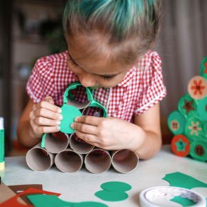 kleines mädchen bastelt zu hause einen adventskalender aus toilettenpapierrollen