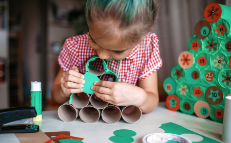 kleines mädchen bastelt zu hause einen adventskalender aus toilettenpapierrollen