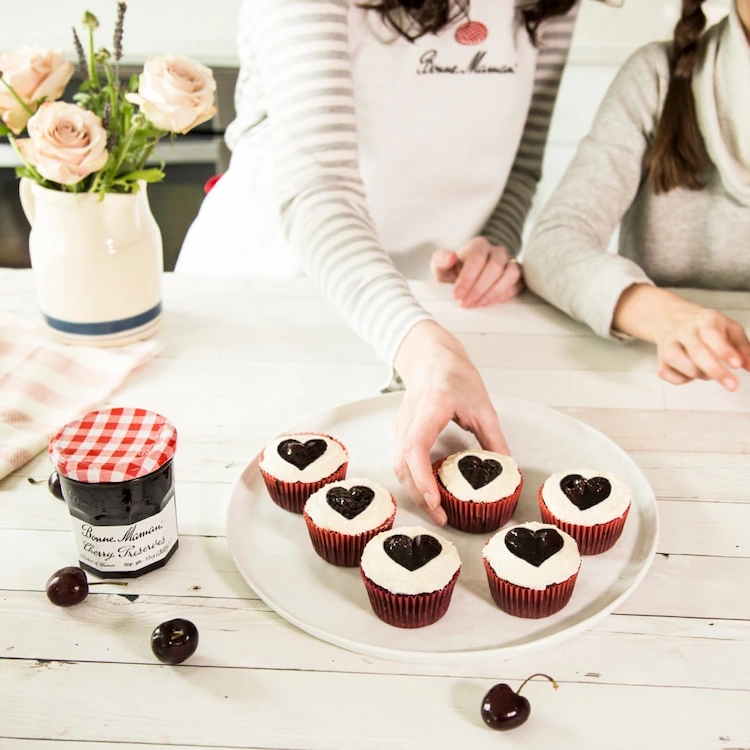 cupcakes mit weißem topping und herzen aus marmelade