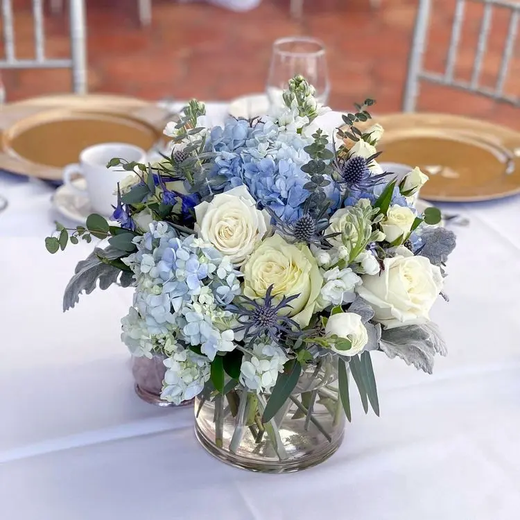blaue hortensien, weiße rosen, disteln und zartgrünes beiwerk