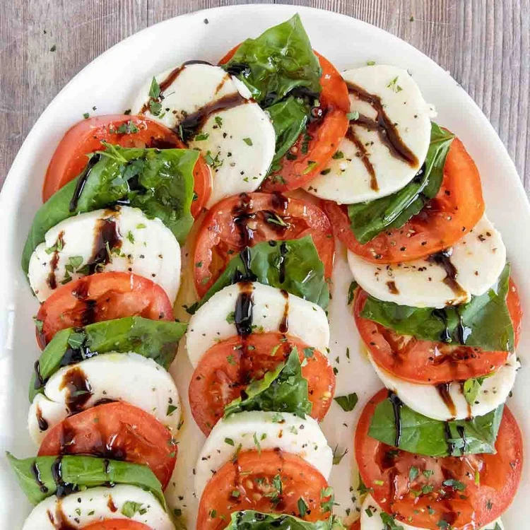 Klassischen Caprese Salat würzen und anrichten