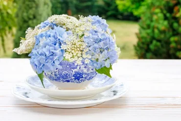 blumengesteck für den tisch mit blauen hortensien