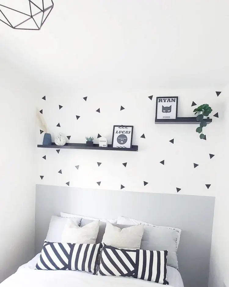 Dezente Wandgestaltung mit schwarzen, kleinen Dreiecken und Fotoleisten auf weißer Wand