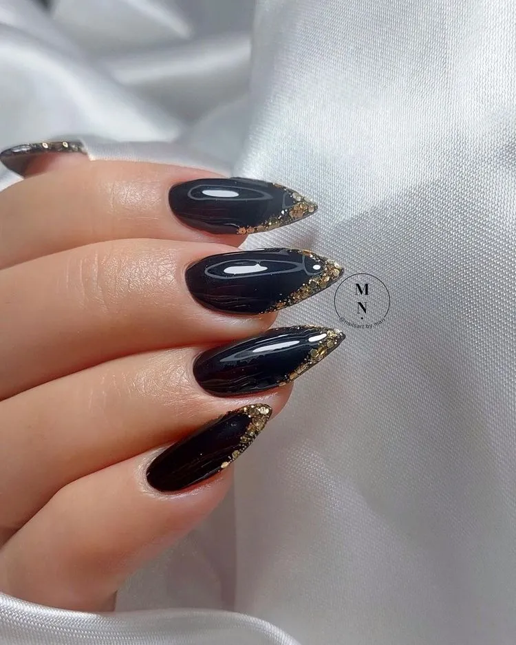 Dramatische schwarze Nägel mit glitzerndem, goldenem Rand