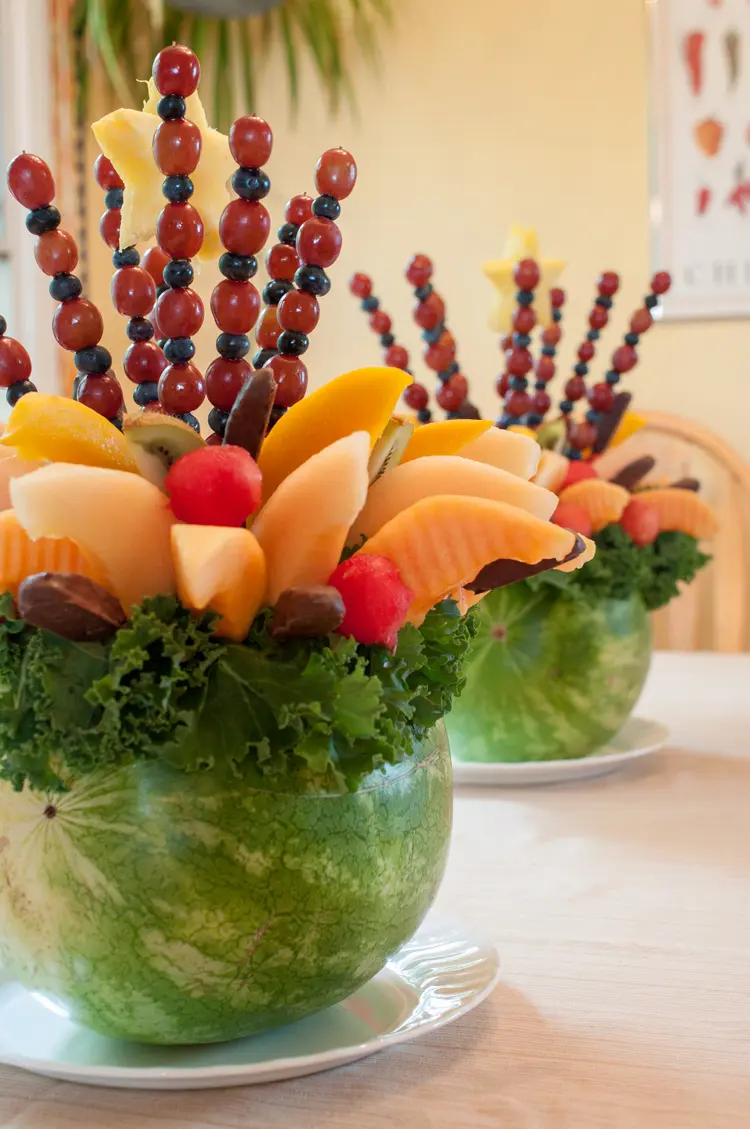 Obststrauß selber machen für den Tisch - Spieße mit Trauben, Melonen und Salatblättern in einer Wassermelone