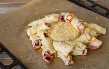 Bestreichen Sie den Blätterteig mit Camembert und Bacon mit Eigelb