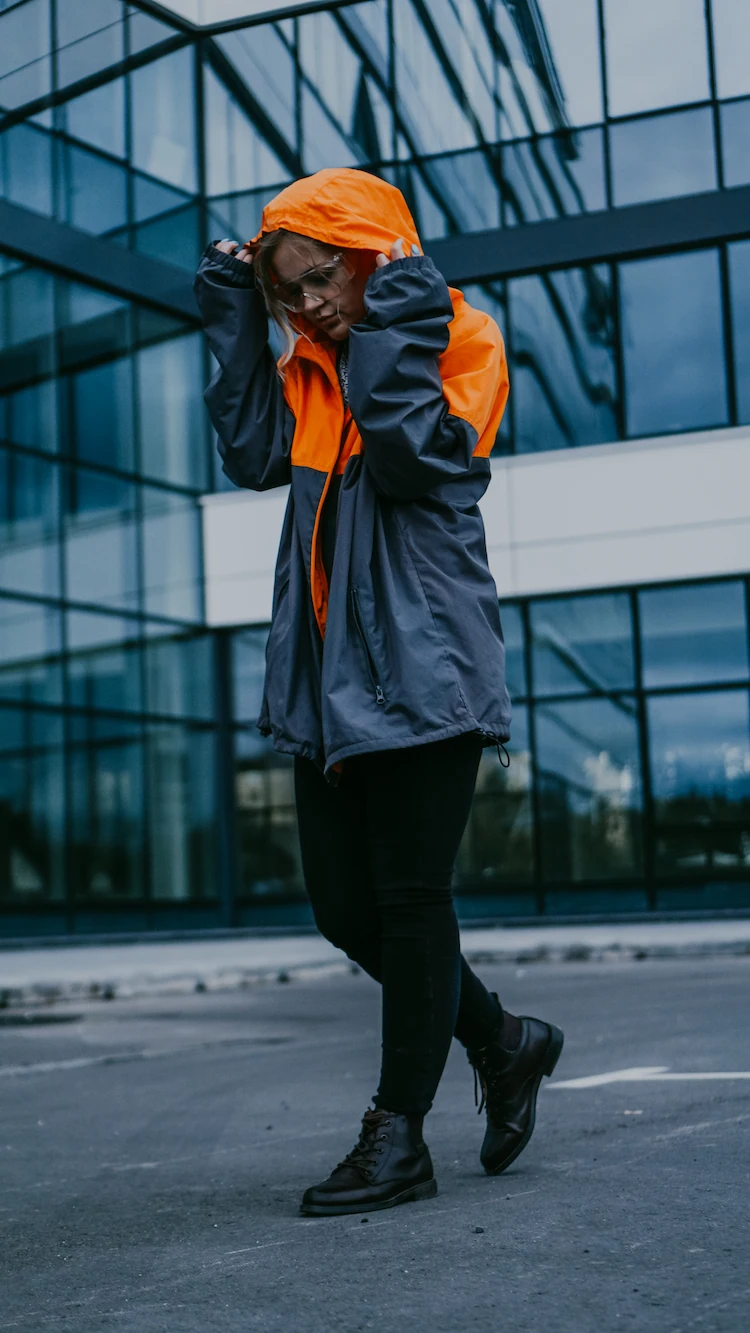 farbblock jacke in orange und grau mit schwarzen hosen und boots