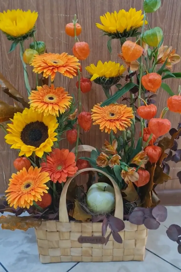 Korb mit Physalis, Sonnenblumen, Chrysanthemen und Apfel