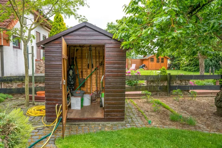 Schaufeln, Rechen und große Gartenscheren an die Wände hängen oder lehnen