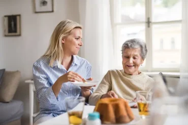 betreuungskraft beim gemeinsamen essen mit seniorin