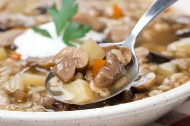 Die Herbstsuppe mit Graupen kann mit Sauerrahm serviert werden