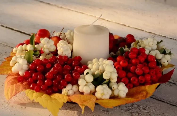 Flache Dekoschale, ausgelegt mit gelben Herbstblättern, Vogelbeeren und Schneebeeren