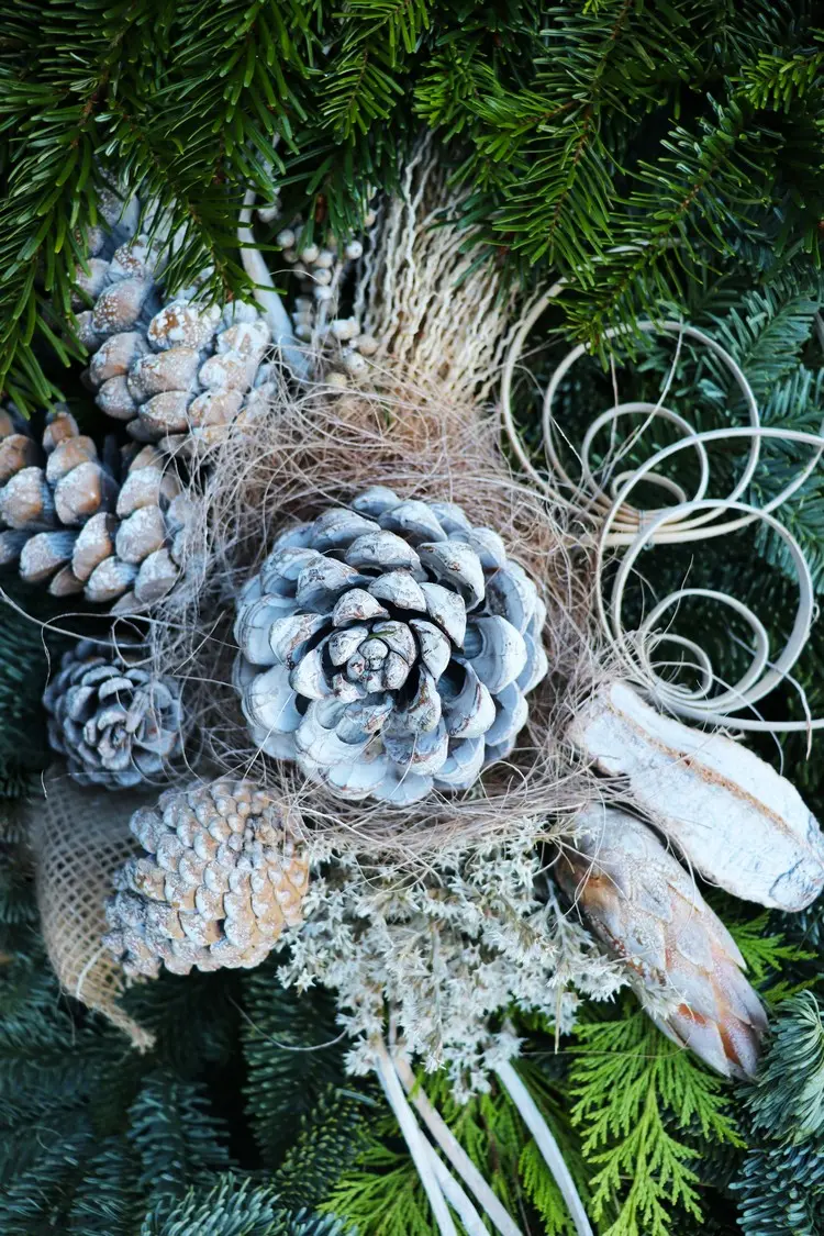 Frostige Optik für ein Gesteck mit Tannenzapfen und gefärbten Trockenblumen