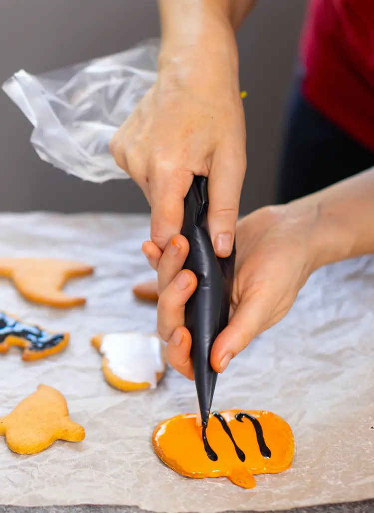 halloween kürbiskekse mit schwarzer glasur dekorieren