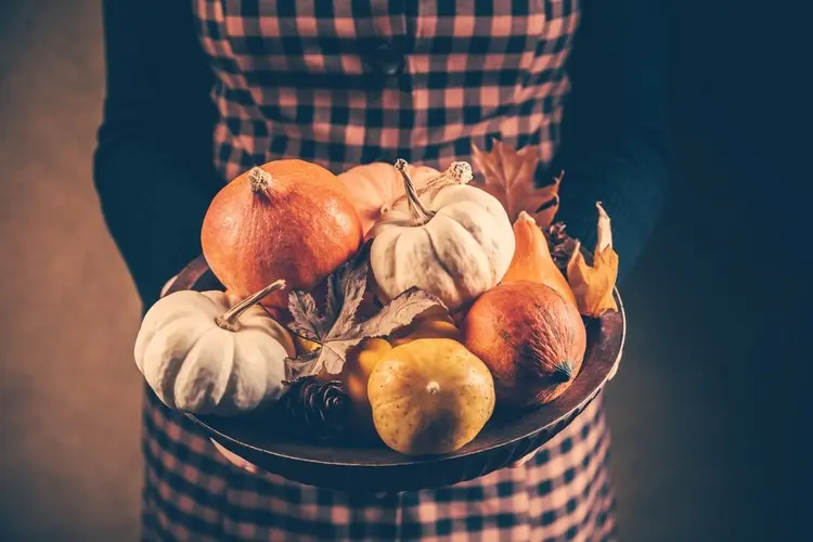 Im Herbst eine Deko mit Kürbissen und trockenen Blättern zusammenstellen