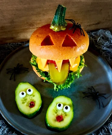 Kürbis-Hamburger mit Zähnen aus Käse und Zunge aus Gurke