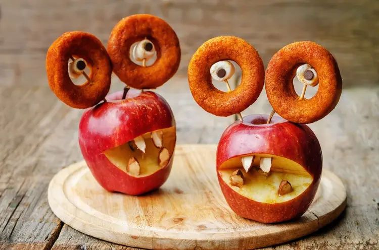 Mini-Donuts und Marshmallows für die Augen eines Apfel-Monsters mit Mandel-Zähnen