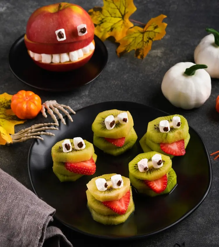 Obstteller zu Halloween mit kleinen Monstern aus Kiwi und Erdbeeren dekorieren