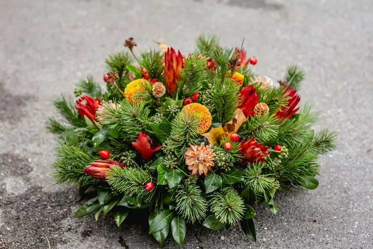 Schönes Gesteck mit Materialien aus der Natur wie Tannengrün, Efeu, Hagebutte und Blumen