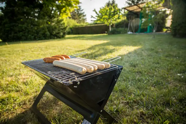 tragbarer holzkohlegrill mit würstchen ideal für camping und picknicks