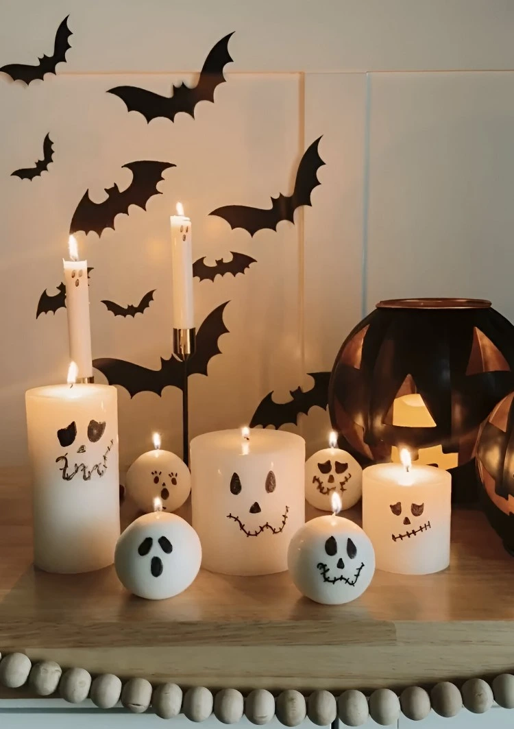 Verschiedene Kerzen mit Geister- und Kürbisgesichtern bemalen
