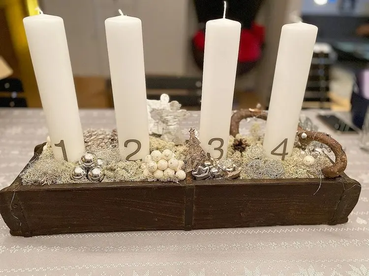 Adventskranz in einer Holzkiste mit langen Kerzen und goldener Deko