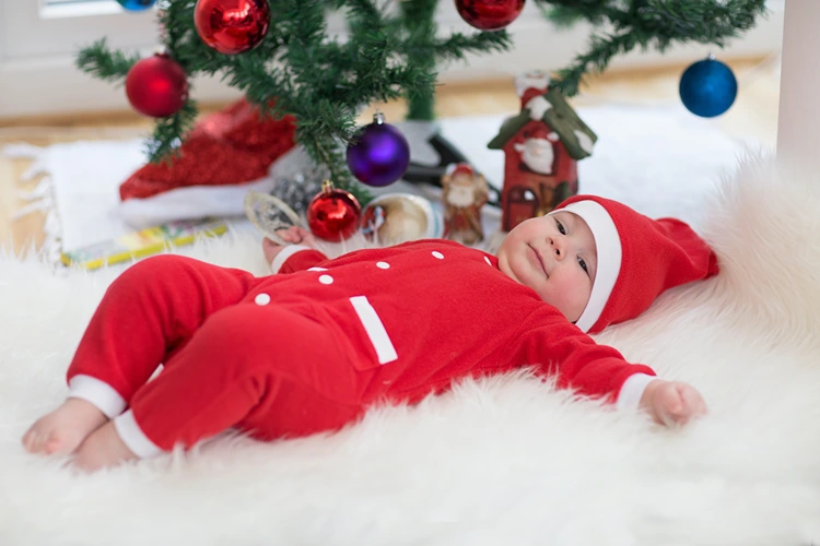 baby als kleiner weihnachtsmann unter dem baum