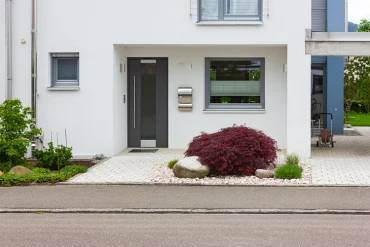 eleganter eingang mit dunkelgrauer tür und dezenter landschaftsgestaltung