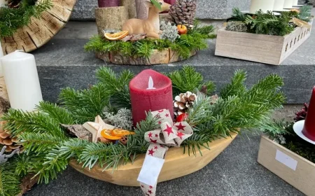 Holzschale mit Tannengrün, roter Kerze und weihnachtlichen Dekorationen