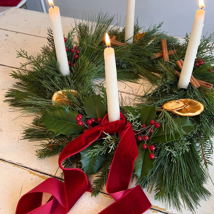 natürlicher adventskranz mit weißen kerzen und roten akzenten