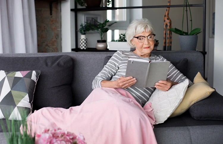 oma entspannt mit einer warmen decke und einem guten buch