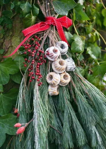 Tannengrün mit Vogelfutteranhängern und Beeren zusammenbinden