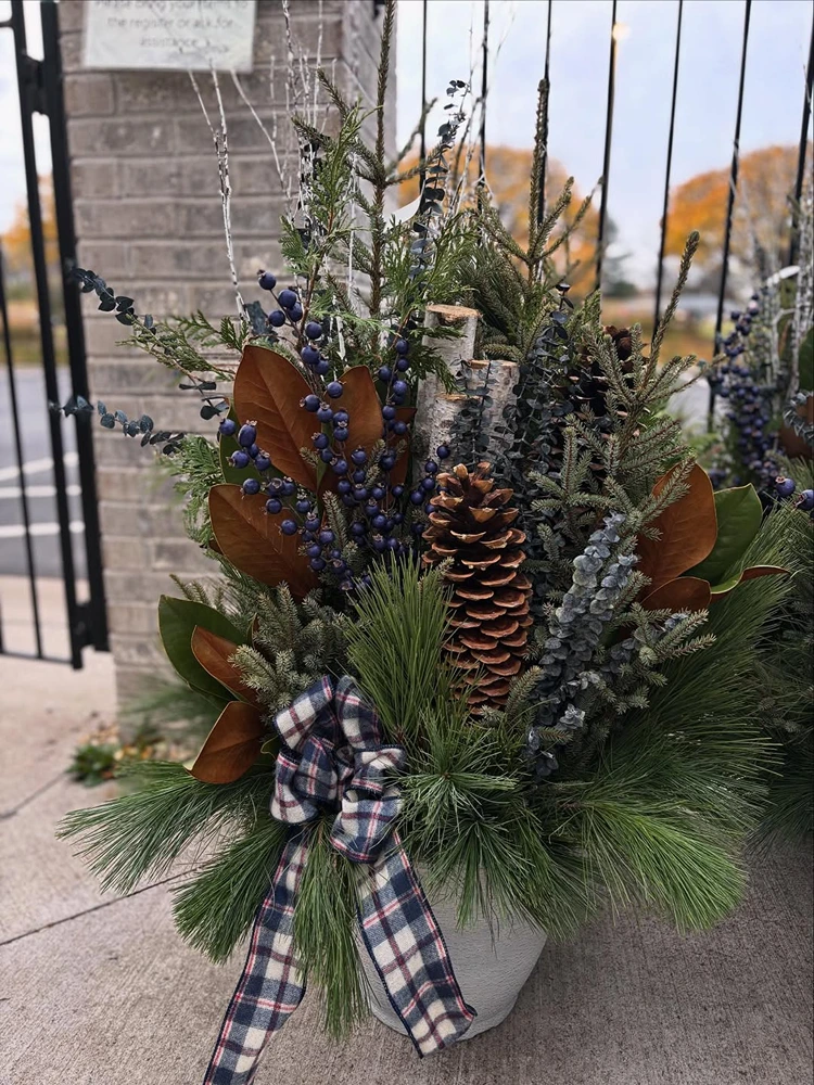 Üppiges wintergesteck im hohen kübel mit großer schleife