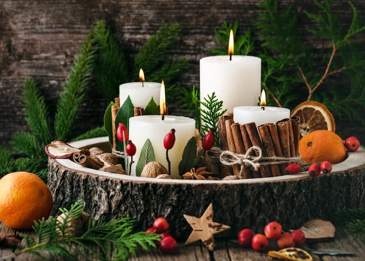 winterliches gesteck mit holzscheibe, kerzen und getrockneten früchten