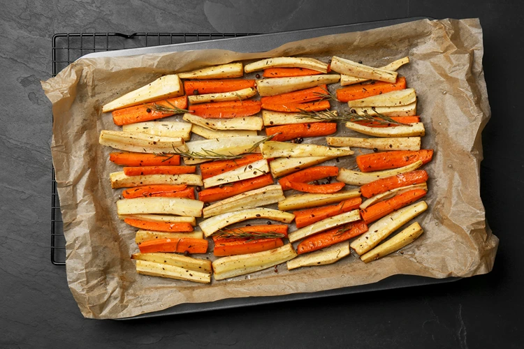 geröstete pastinaken und möhren fertig auf dem backblech mit kräutern