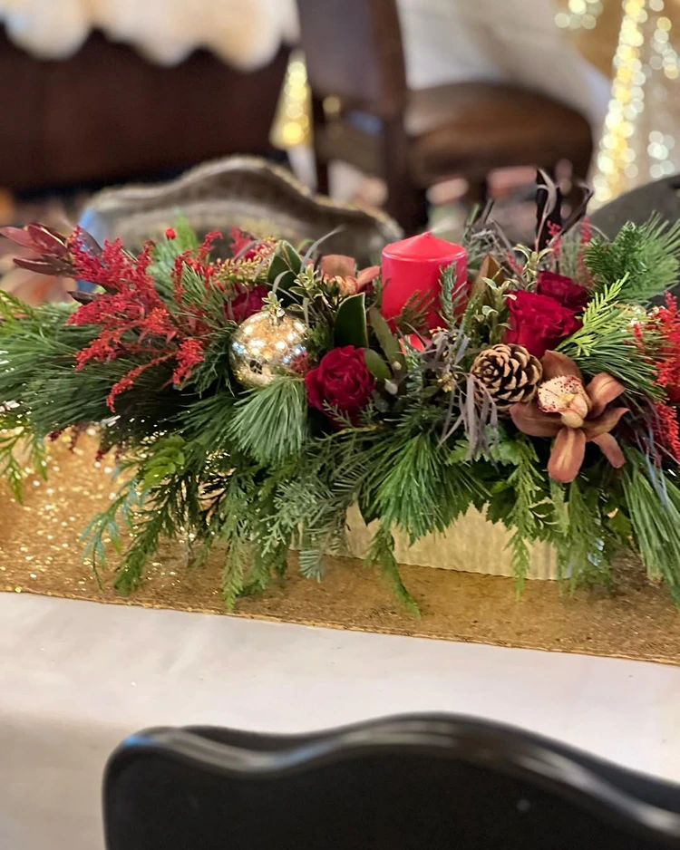 längliches tischgesteck mit roter kerze