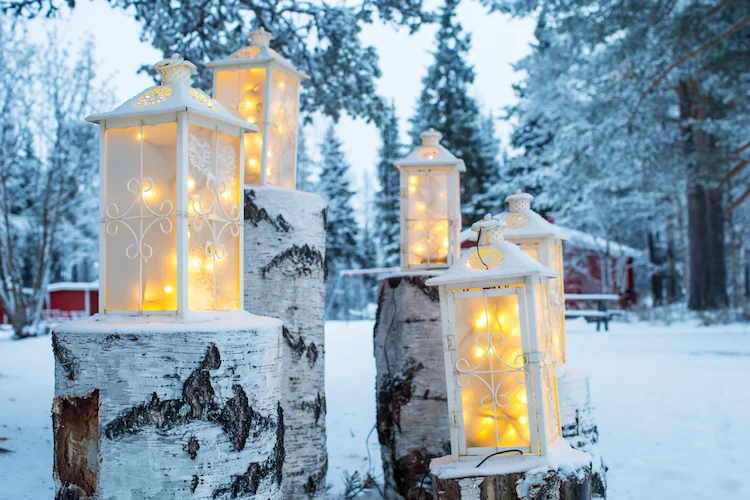 winterdeko für den hauseingang mit laternen und baumstämmen