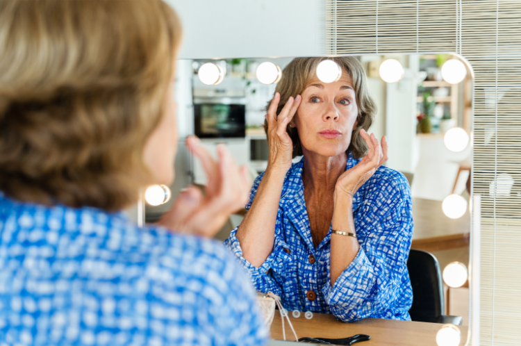 Ältere frau, die sich am schminktisch schminkt