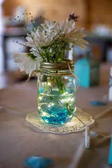 frühlingsdeko für tisch mit einmachglas, blumen und lichterkette