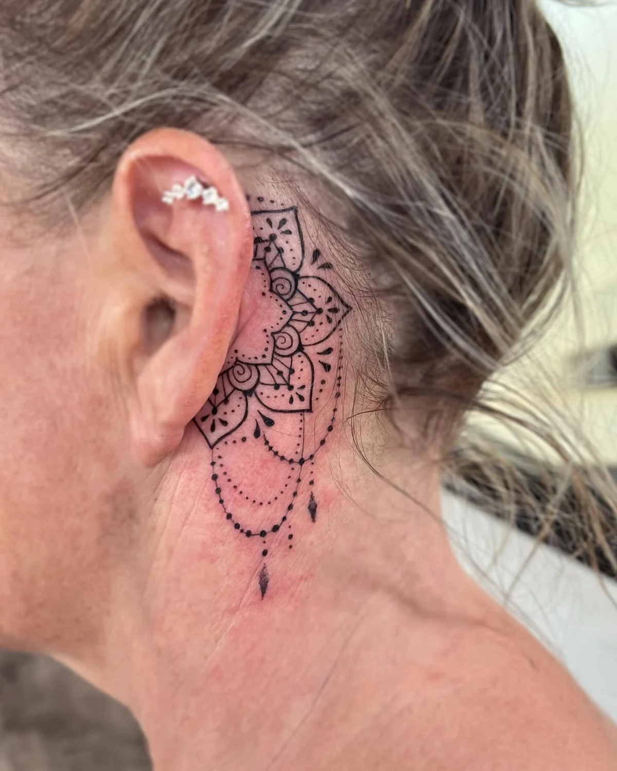 mandala tatoo hinter dem ohr einer älteren frau