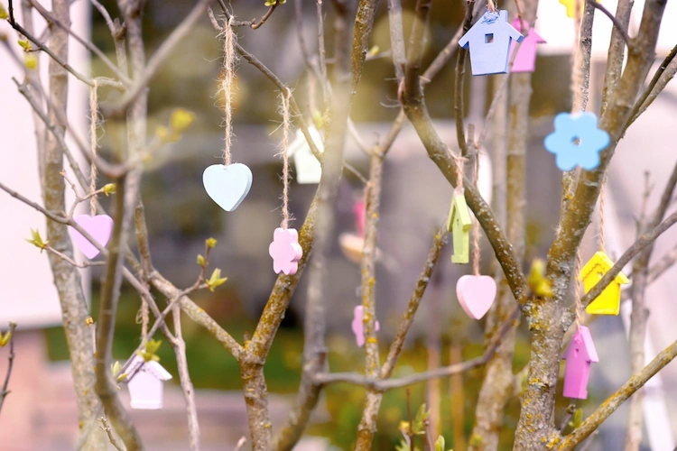 frühlingshafte dekoelemente aus holz an die bäume aufhängen