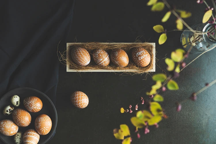 schlicht gestaltete ostereier in einer kiste mit stroh präsentiert