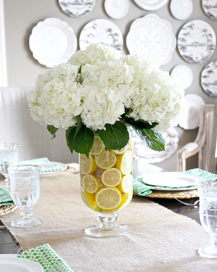 vase mit schwimmenden zitronenscheiben weiße hortensien